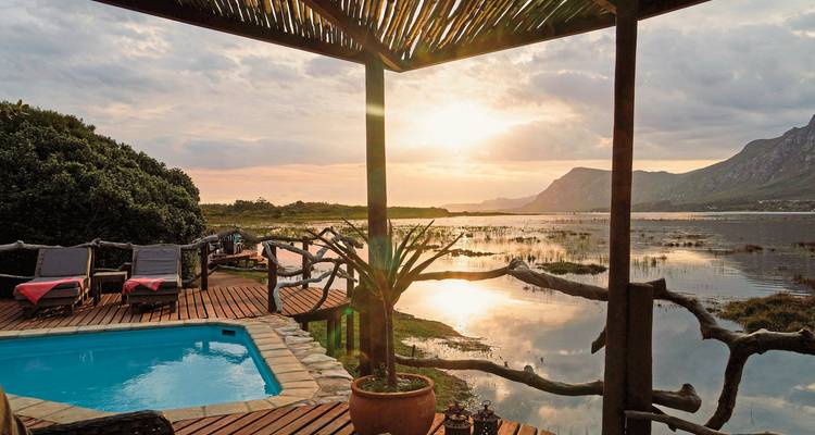 Luxuriöser Poolblick über eine Lagune bei Sonnenuntergang.