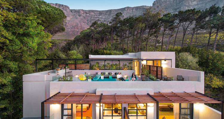 Moderne Villa mit Dachpool vor Bergkulisse.