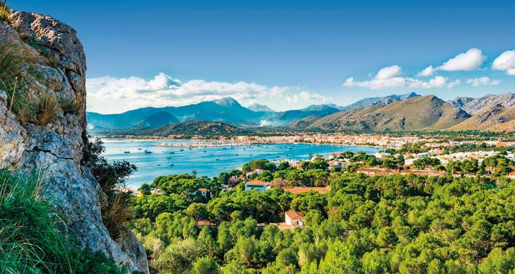 Une belle vue côtière avec des montagnes, une végétation luxuriante et une baie avec des bateaux.