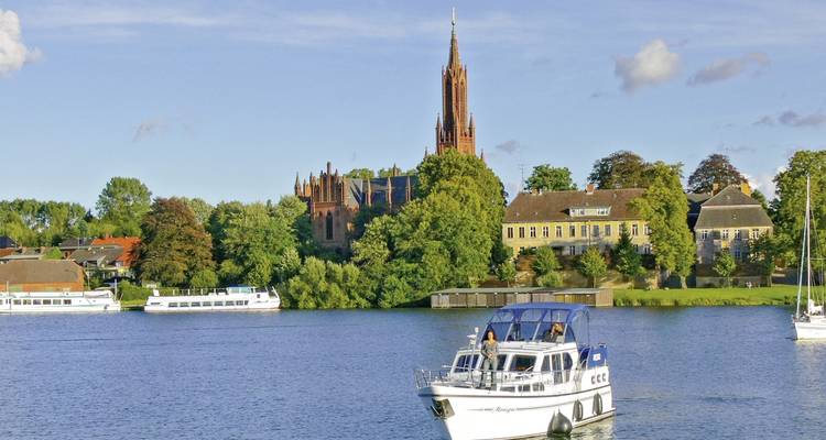 Boot auf einem Fluss mit einer Kathedrale und Gebäuden am gegenüberliegenden Ufer.