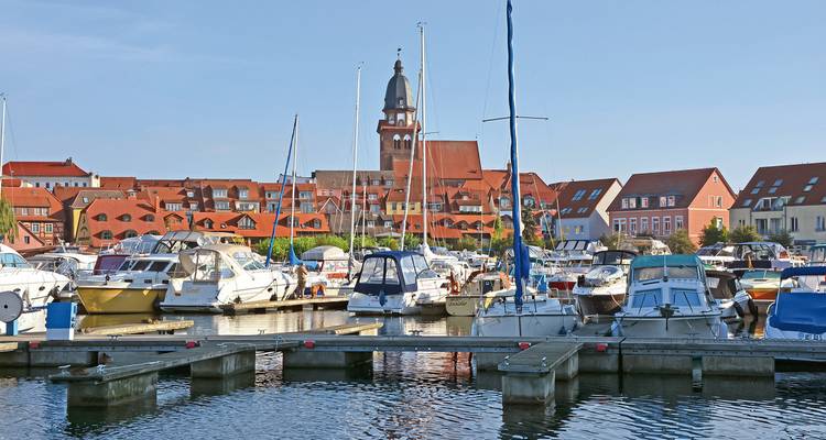 Marina mit Segelbooten und Gebäuden im Hintergrund.