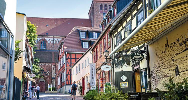Malerische Kopfsteinpflasterstraße mit bunten Gebäuden und Touristen.