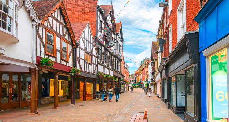 Calle peatonal encantadora flanqueada por edificios Tudor de entramado de madera y tiendas boutique