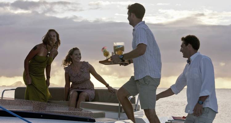 Menschen, die bei Sonnenuntergang Drinks auf einer Yacht genießen.