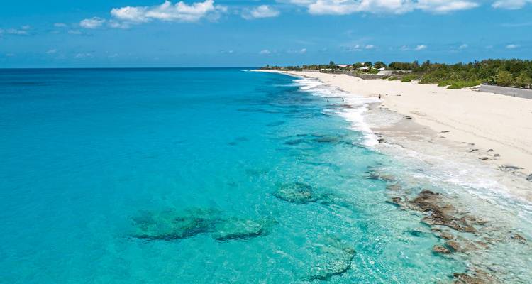 Türkisfarbener Ozean mit einem Sandstrand, der sich entlang der Küste erstreckt.