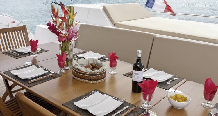 Configuration de salle à manger sur un bateau avec vue sur l'océan et un drapeau français.