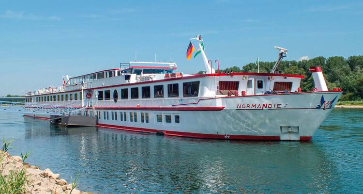 Un grand bateau de croisière fluviale accostant au bord de la rivière.
