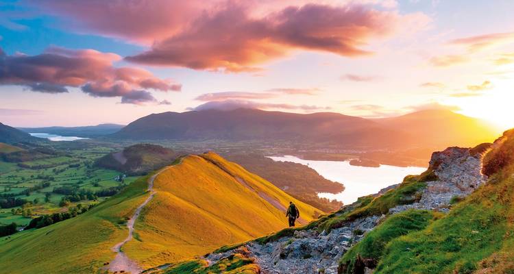 Hiker on a ridge overlooking a valley at sunset.