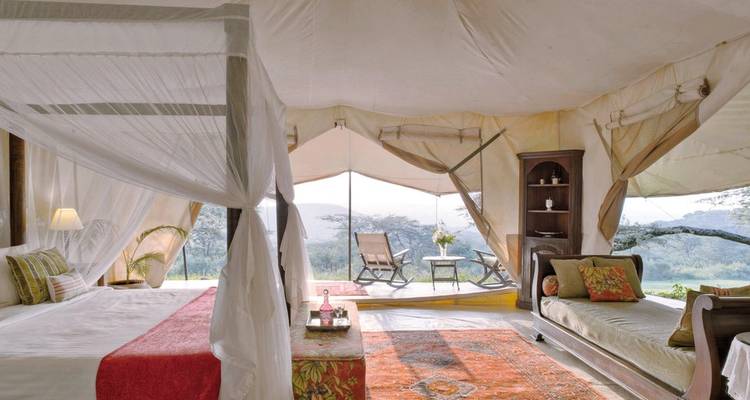 Intérieur de lodge luxueux avec lit à baldaquin et vue ouverte sur la nature.