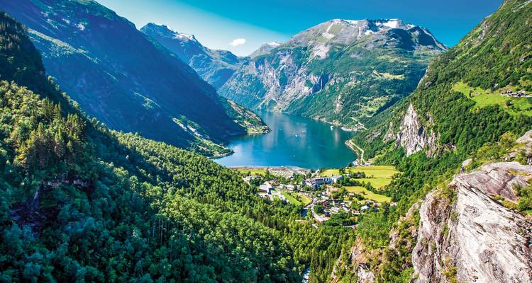 Tiefer Fjord mit üppig grünen Bergen und Dorf.
