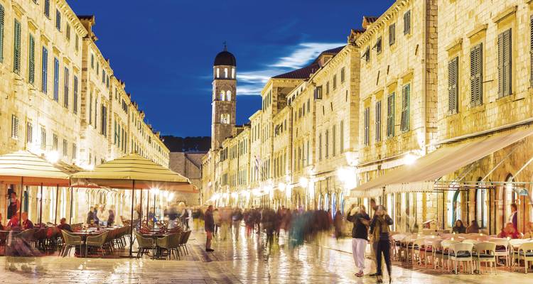 Busy city street at night with restaurants and shops lit up.
