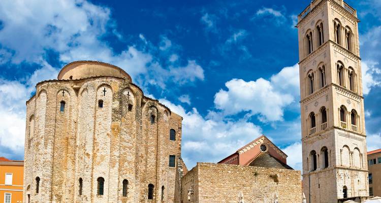 Historic stone building with a tall bell tower under a blue sky.