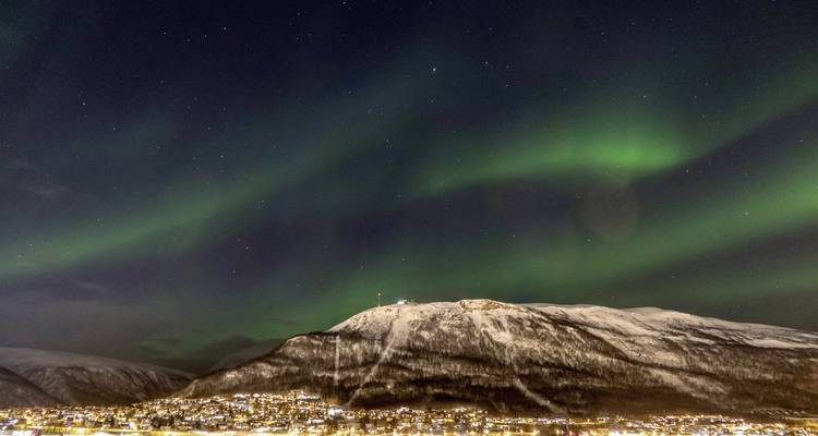 Aurores boréales illuminant une montagne enneigée la nuit.