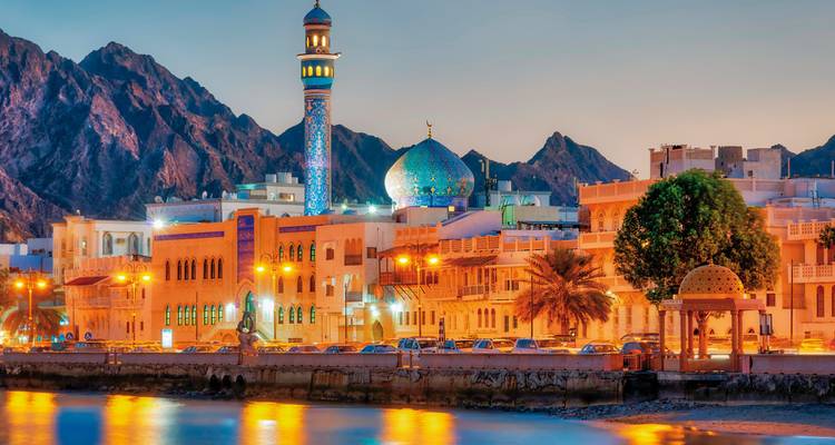 El vibrante horizonte de Mascate al anochecer que presenta una mezquita con una cúpula azul.