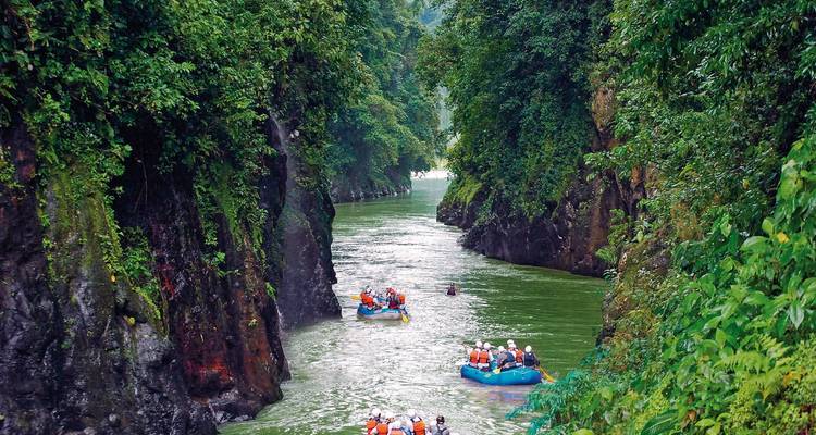 Radeaux naviguant dans un canyon fluvial entouré d'une végétation luxuriante.