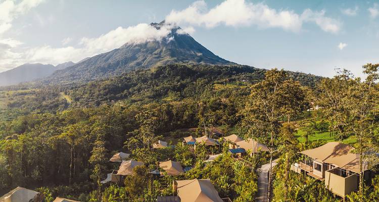 Volcan avec une végétation luxuriante et un établissement à la base.