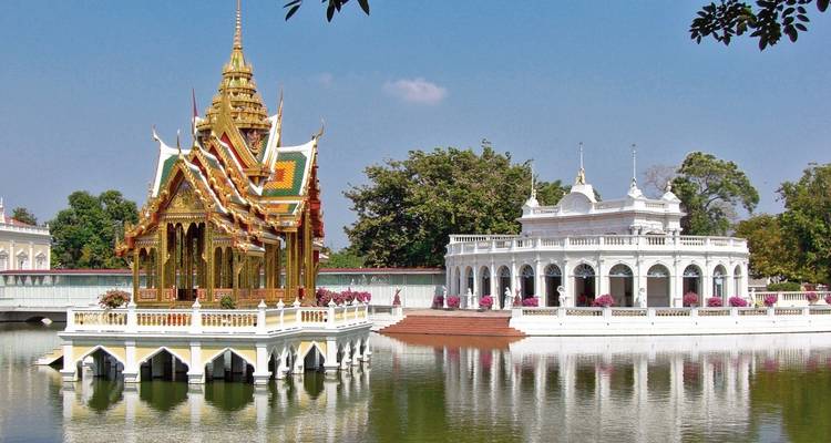 Temple majestueux sur l'eau avec des jardins luxuriants en arrière-plan.