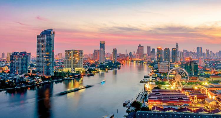 Vibrant city skyline reflected in a river at dusk.