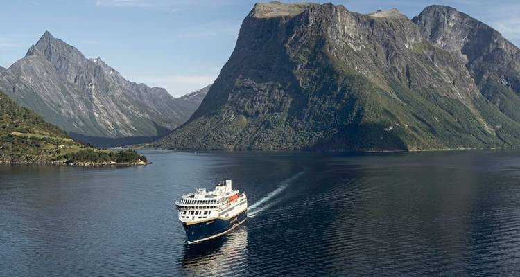 Paysage de fjord avec un navire de croisière et des falaises imposantes.