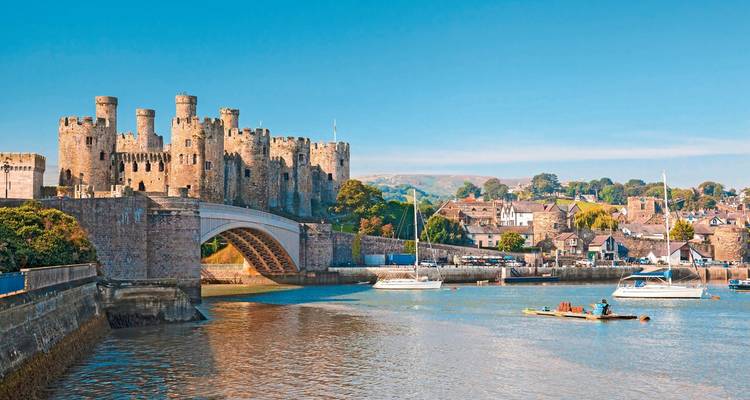 Vue sur le port avec un château historique et des bateaux amarrés à proximité.