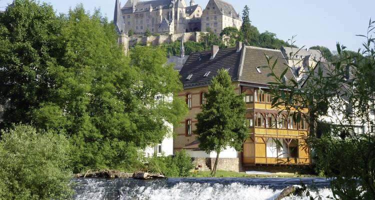 Château sur une colline au-dessus d'une cascade avec une végétation luxuriante.