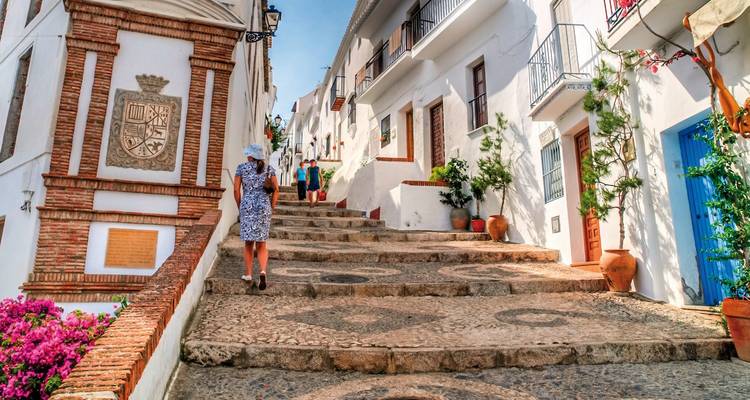 Charmante steile Kopfsteinpflasterstraße mit Menschen, umgeben von weißen Gebäuden.
