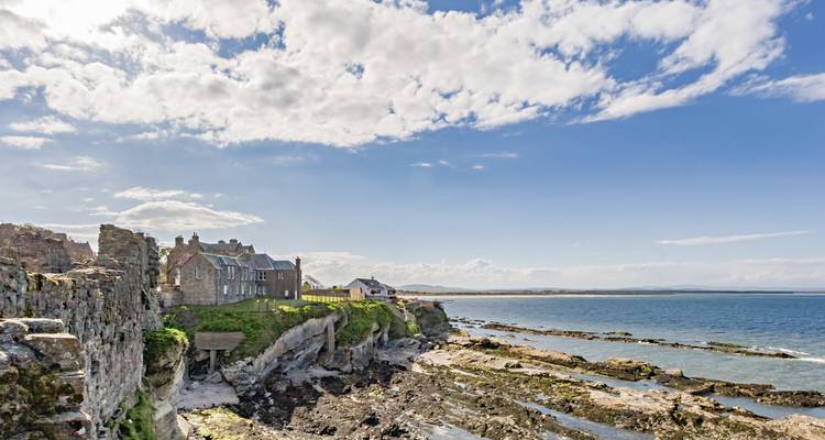 Paisaje costero con ruinas medievales y rocas.
