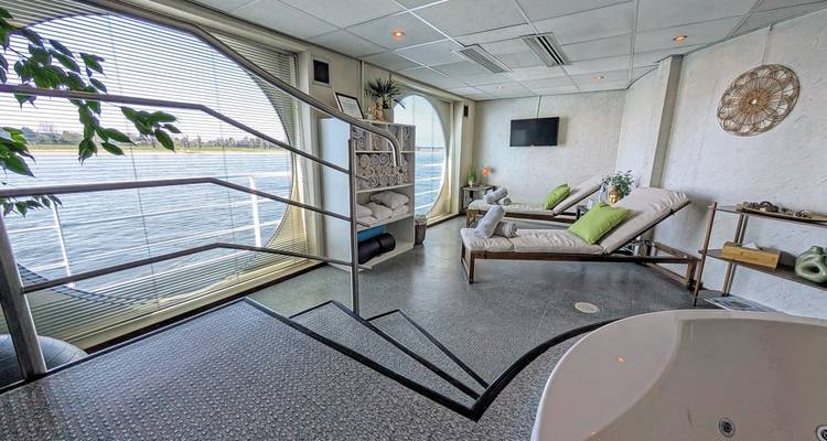Interior view of a spa room on a river cruise ship with lounge chairs and river views.