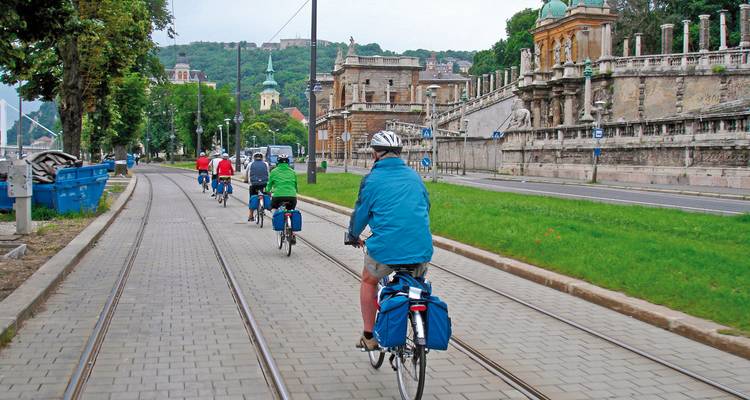 Un groupe de cyclistes roule à travers une ville historique aux rues pavées.