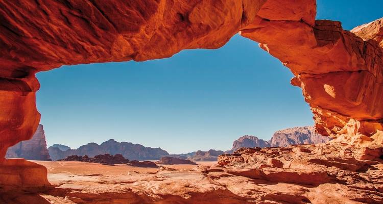 A dramatic desert landscape with rock formations under a clear blue sky.