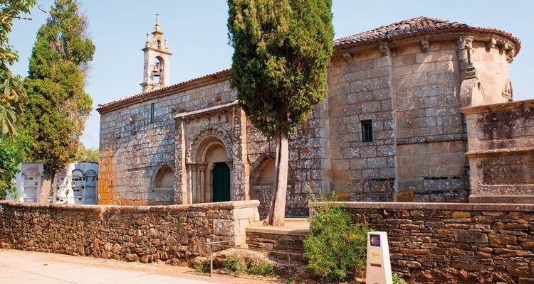 Historic church with a stone facade, surrounded by trees.