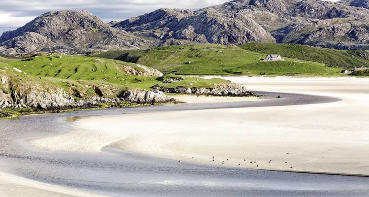 Sandy beach with gentle hills and rocky formations.