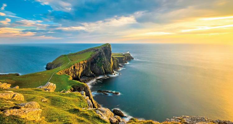 Dramatic cliffs and ocean in a golden sunset with clear skies.