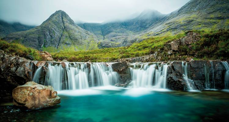 Fairy Pools with clear water flowing over rocks and mountains in the background.