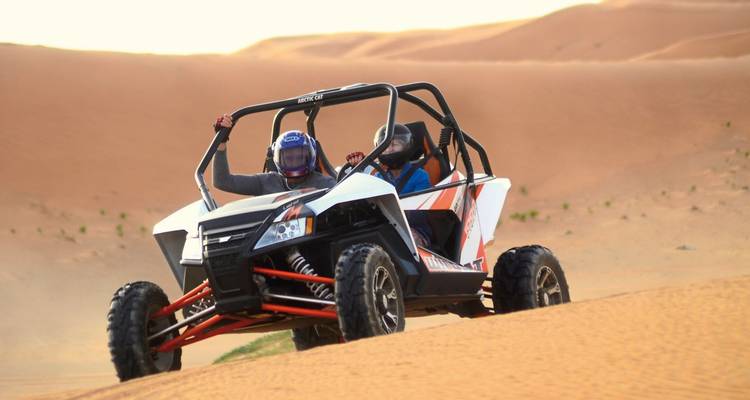 Menschen, die mit einem Strandbuggy über Wüstensanddünen fahren.