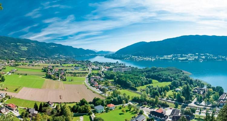 Vue aérienne d'un lac entouré de villages et de montagnes.