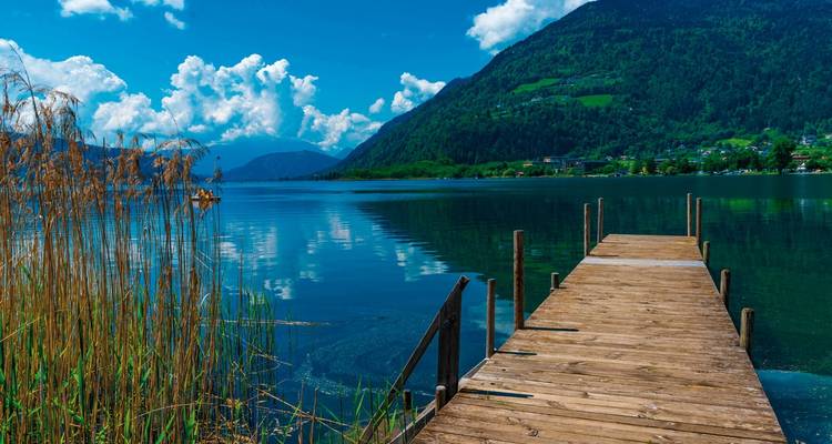 Une jetée en bois sur un lac bleu clair avec des montagnes.