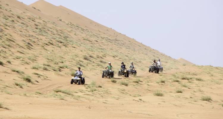 Groupe de personnes conduisant des VTT à travers les dunes de sable.