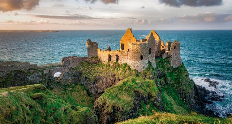 Ruines du château de Dunluce au bord d'une falaise escarpée surplombant la mer.