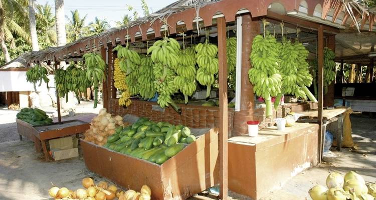 Marktstand met bananen en groene producten.