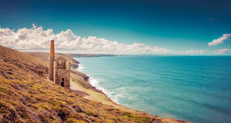 Bâtiment de machine en ruine sur une falaise surplombant la mer.