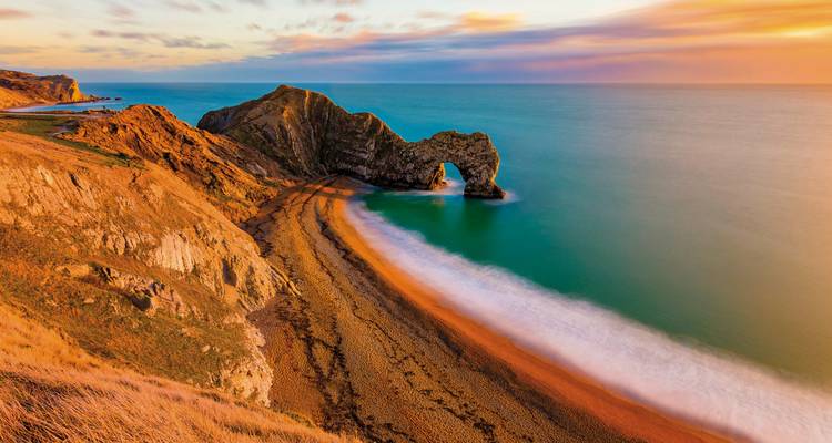 Arche rocheuse de Durdle Door au-dessus de la mer au coucher du soleil.