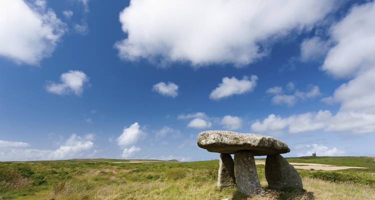 Structure mégalithique en pierre dans un paysage herbeux.
