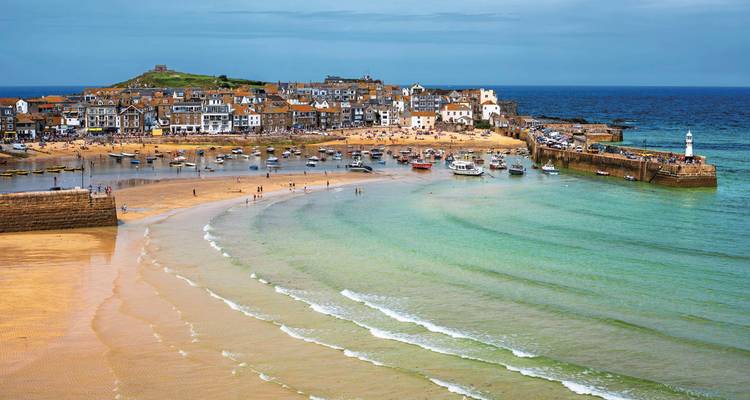 Puerto arenoso con curvas y el pueblo de St Ives rodeados de aguas turquesas en un día despejado.