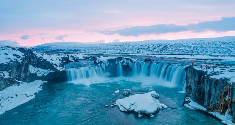 Cascade gelée dans un paysage enneigé au crépuscule.