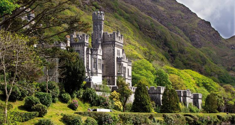 Historic stone castle set against lush green mountains.