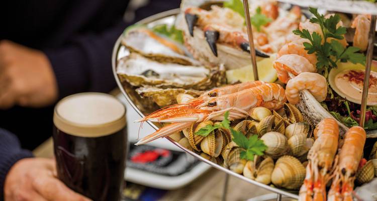 Meeresfrüchteplatte mit einem Pint dunklem Bier, auf einem Tisch serviert.