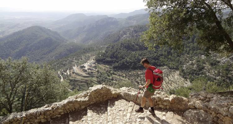 A hiker descending stone steps with valley views.