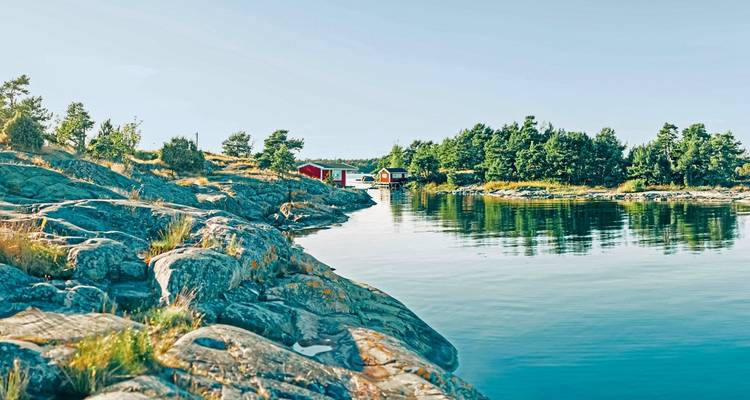 Scenic coastal view with rocky shores and red cabins.