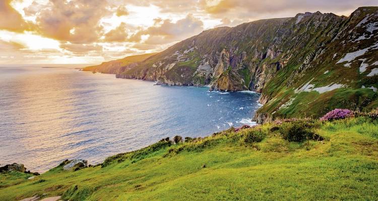 Une falaise côtière avec une végétation luxuriante et un ciel éclatant.